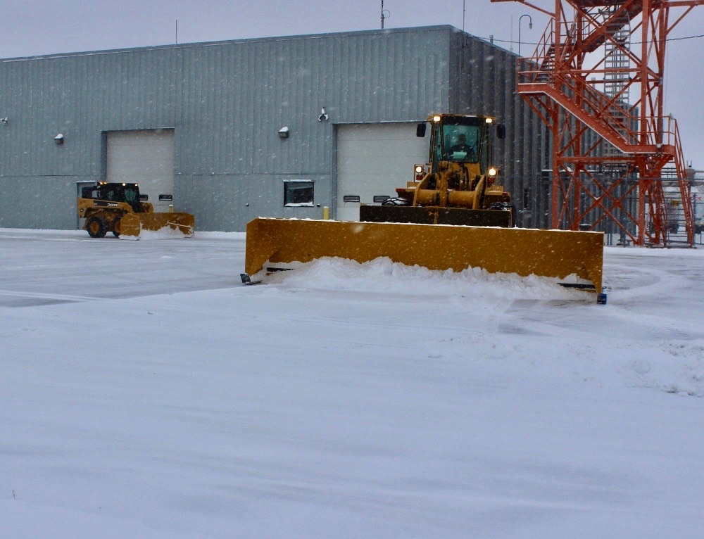 A yellow payloader plowing snow.