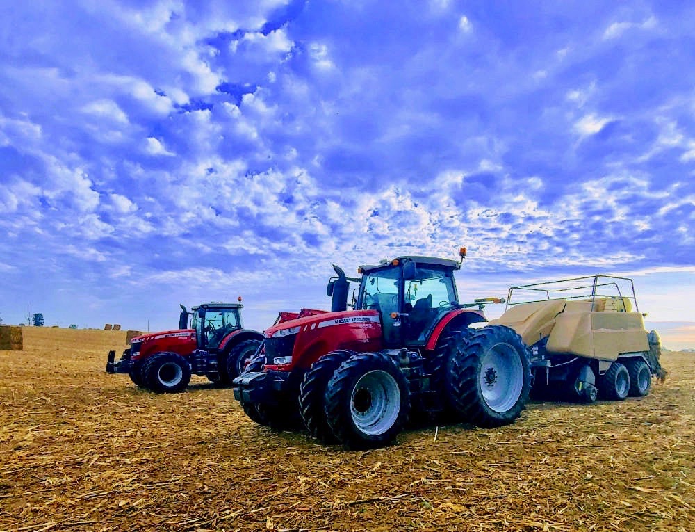 Big tractors bailing field crops on the family farm